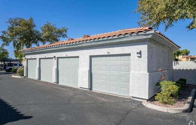 A two-car garage with a red tile roof and a small tree in front.