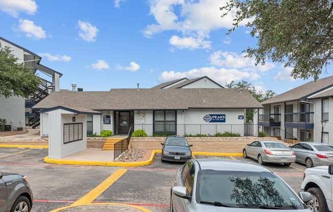 a white building with a gray roof and a parking lot in front of it