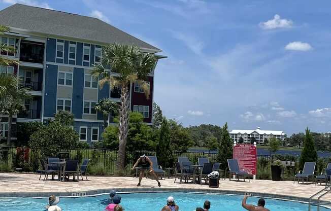 a group of people playing in a pool with a building in the background