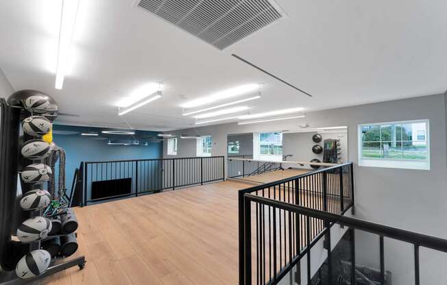 A gym with a row of exercise balls on the left and a balcony on the right.