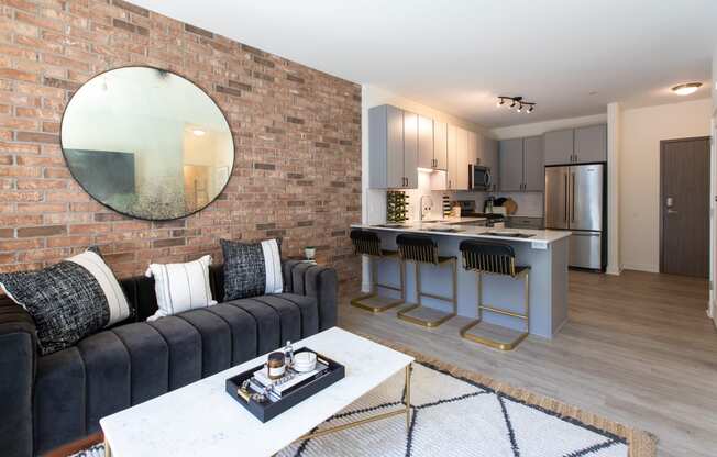 a living room with a couch and a coffee table in front of a kitchen with an island