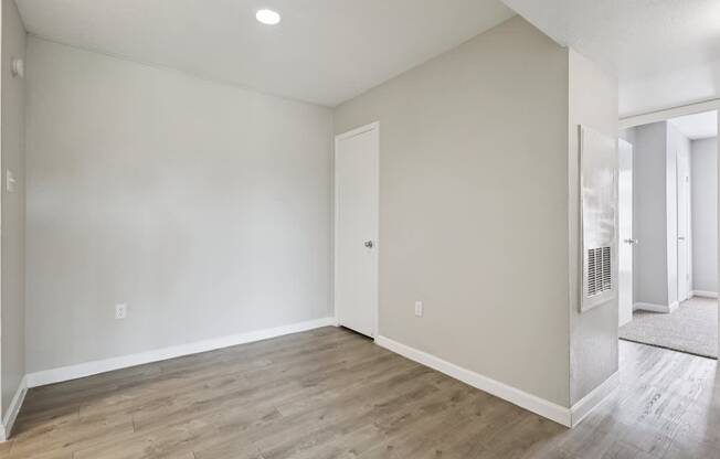 A room with a wooden floor and a door on the left side.