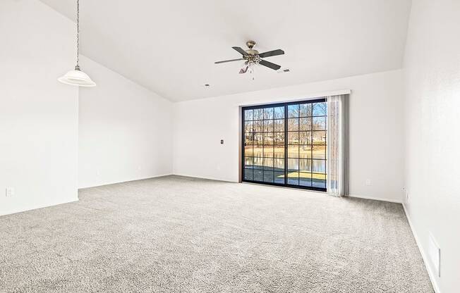 A spacious living room with a high ceiling, ceiling fan and a sliding glass door leading to a patio at Tanglewood Apartments, Oak Creek, WI