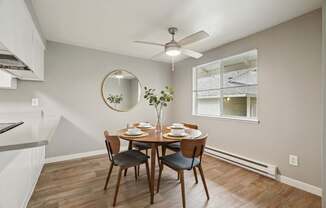 A dining room with a round mirror and a table set for four.