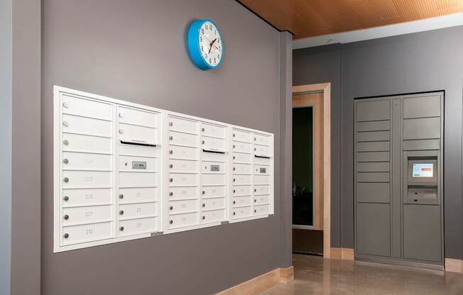 A wall of mailboxes with a clock above them.