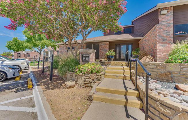 A house with a stone wall and steps leading to the front door.
