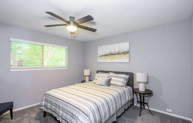 A bedroom with a bed, two lamps, and a painting on the wall.