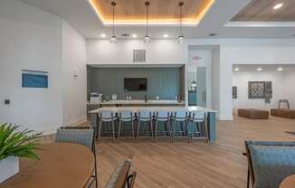 a communal area with a bar and chairs in a room with a table and chairs