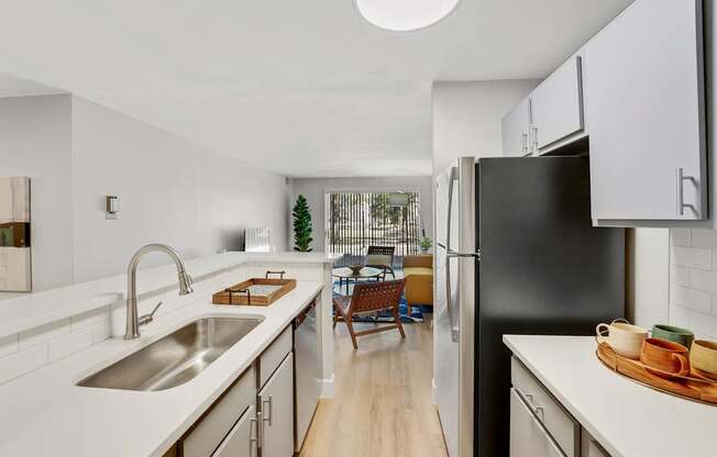 A modern kitchen with a black refrigerator and wooden floors.