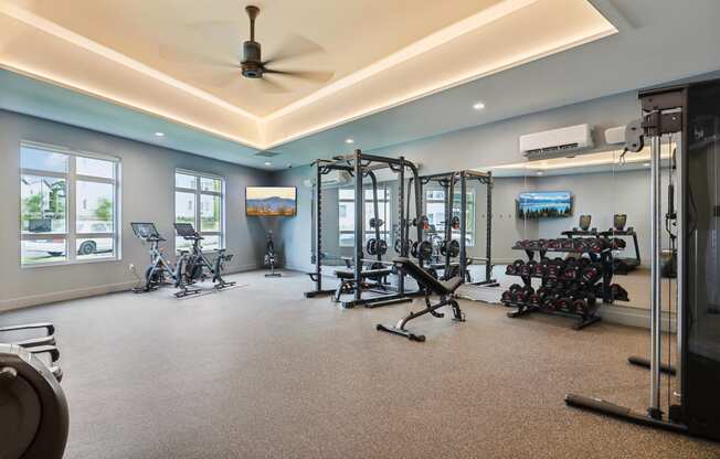 a gym with weights and other exercise equipment on the floor and windows