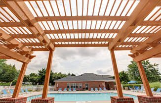 A wooden pergola overlooks a swimming pool.
