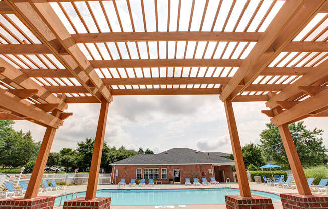 A wooden pergola overlooks a swimming pool.