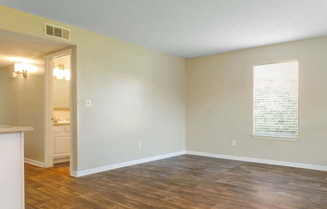 an empty room with hardwood floors and a large window