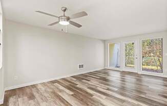 A room with a ceiling fan and wood flooring.