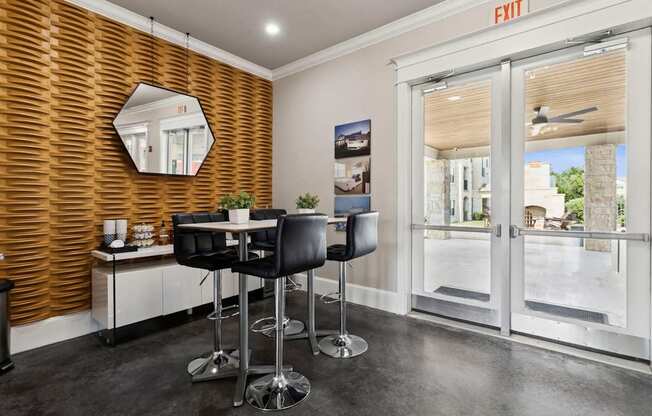 A room with a wooden wall and a mirror above a table with chairs.