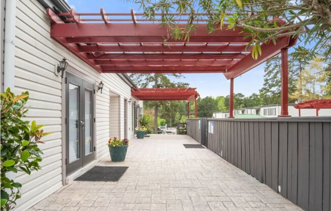 the covered walkway of a white house with a red roof