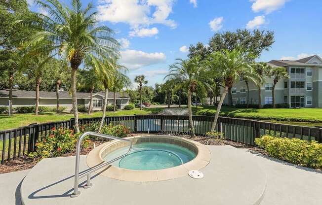 A small pool surrounded by palm trees and a metal fence.