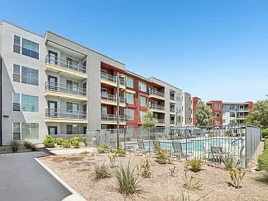 A modern apartment complex with a pool in the foreground.