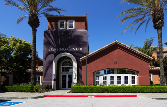 A Leasing Center with a red brick building and palm trees in front.