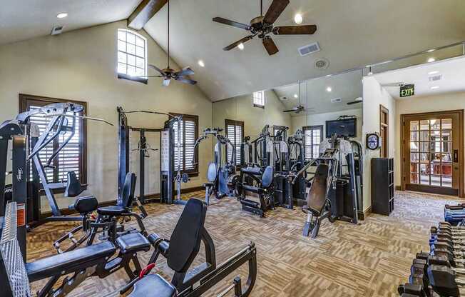A gym with a variety of equipment including treadmills, weights, and a bench press.