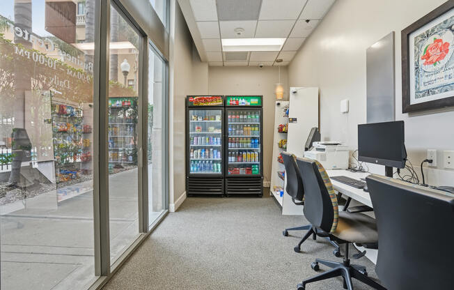 A room with a vending machine, chairs, and a desk.