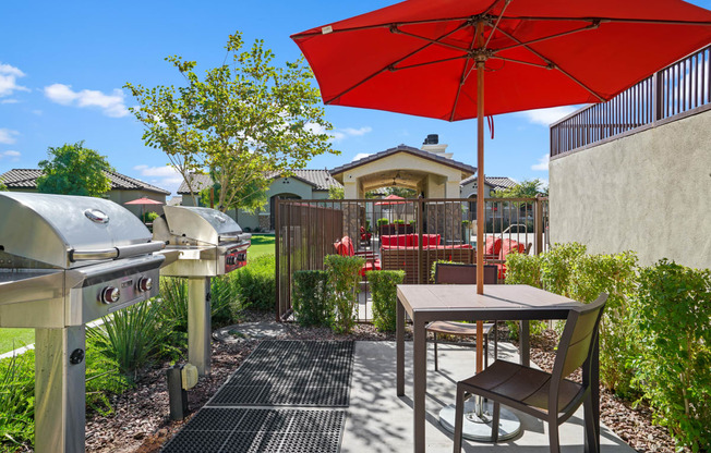 a patio with an umbrella and a table with chairs and a grill