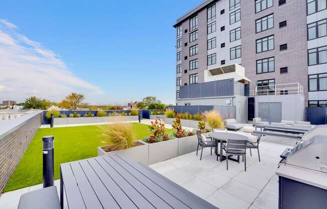 a patio with a table and chairs on a roof terrace with an apartment building