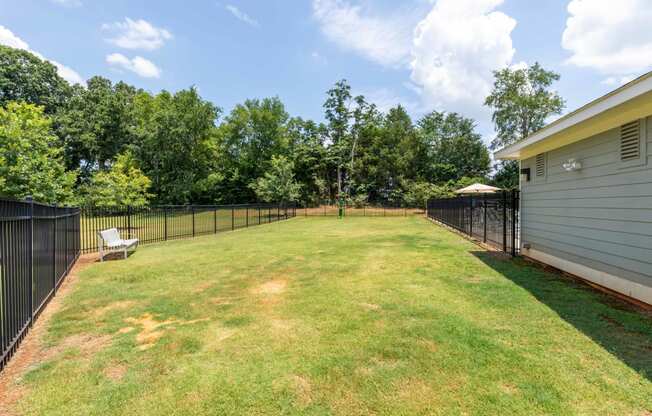 the backyard is fenced in and has a lawn and a fence