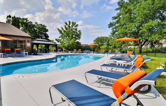 A pool with sun loungers and a gazebo in the background.