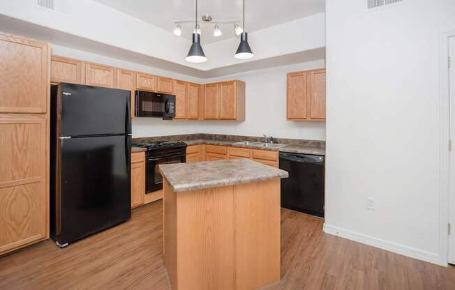 A kitchen with wooden cabinets and a black refrigerator.
