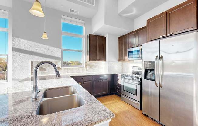 A modern kitchen with a stainless steel refrigerator and a marble countertop.