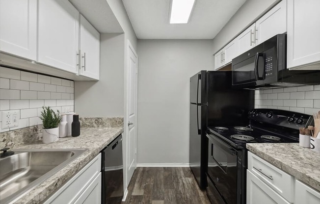 a kitchen with white cabinets and black appliances