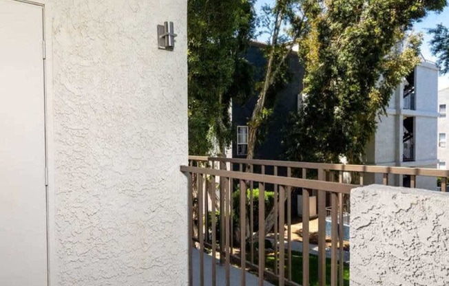 A white wall with a door and a metal railing.