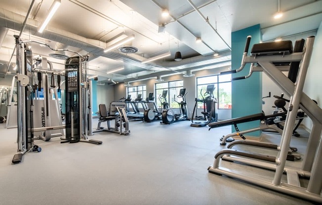 a gym with cardio equipment and weights on the floor