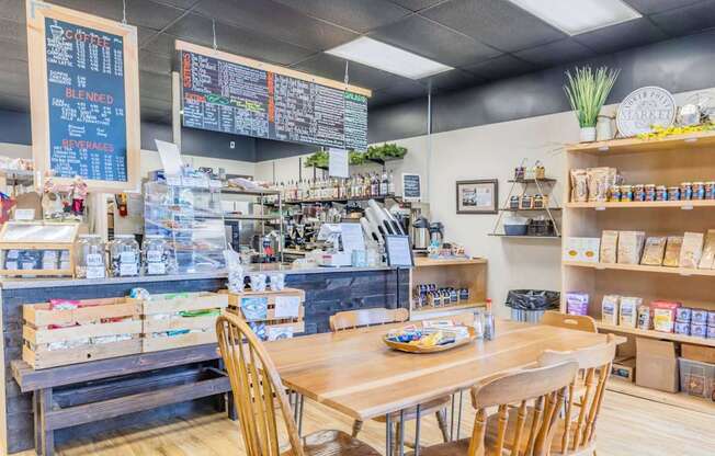 A coffee shop with a wooden table and chairs in the foreground at Spyglass Hill Apartments, Bremerton, 98337