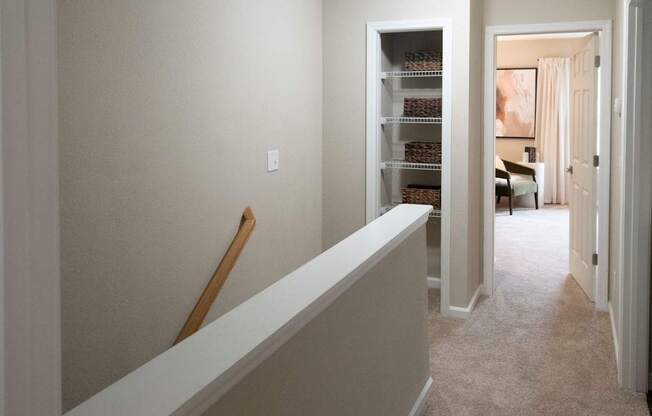 A hallway with a white wall and a white bench.