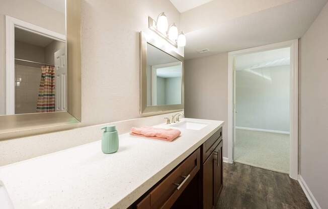 A bathroom with a sink, mirror, and a green vase.