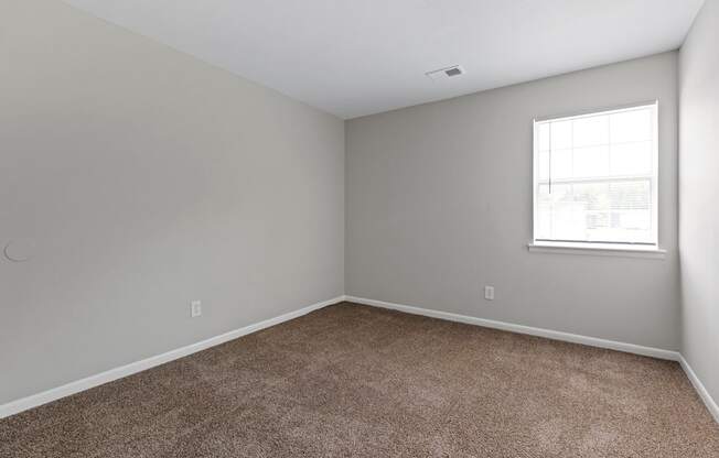 an empty room with carpet and a window