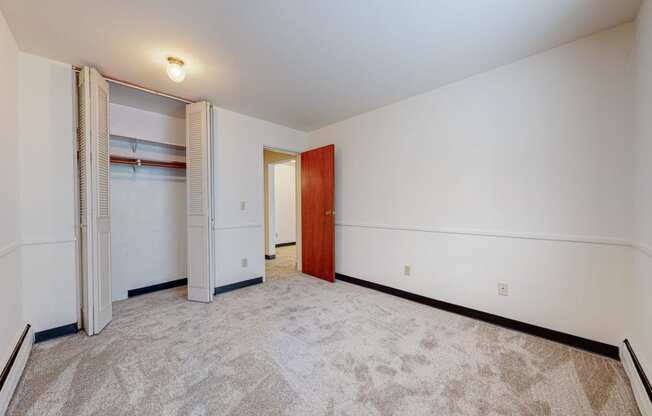 a bedroom with white walls and a closet with a wooden door