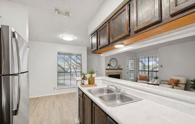 A kitchen with a stainless steel refrigerator and a marble countertop.