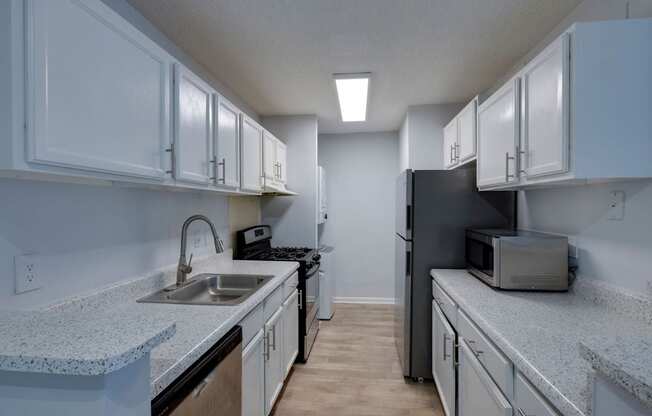 A kitchen with white cabinets and a black refrigerator.