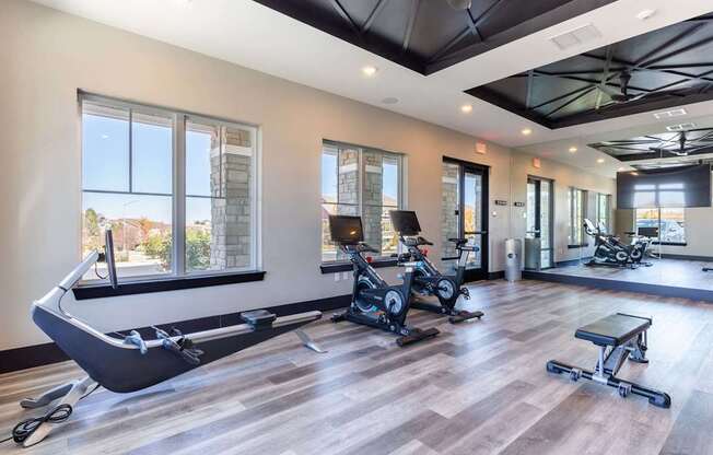 A gym with a rowing machine, treadmill, and weights.