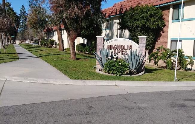 Mature trees and landscaping in front of Magnolia Apartments in Riverside, California.