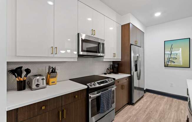 A modern kitchen with white cabinets and a wooden floor.