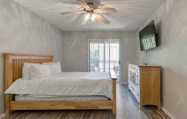 A bedroom with a bed, a dresser, and a ceiling fan.