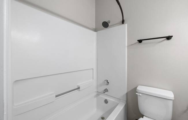 a white bathroom with a white toilet and a bath tub