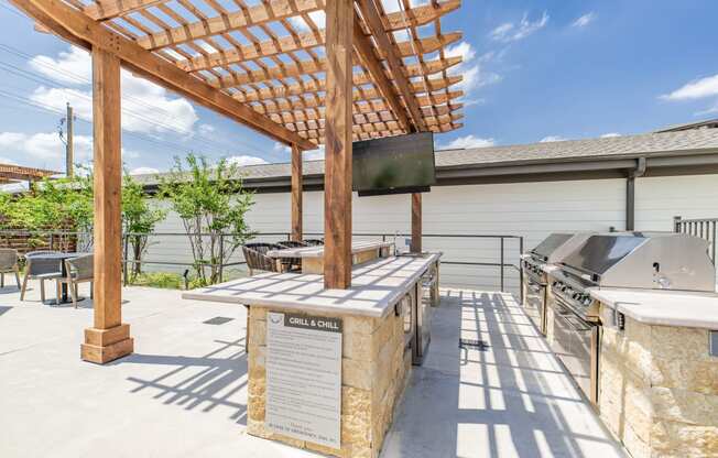 the outdoor patio has a grill and a table with a tv