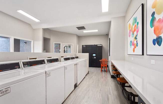 A laundry room with washers and dryers on the left and a bench with chairs on the right.