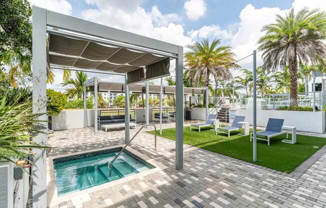 a patio with a pool and chairs and palm trees