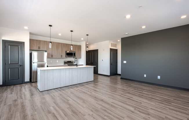an open kitchen and living room with wood flooring and a white island with a
